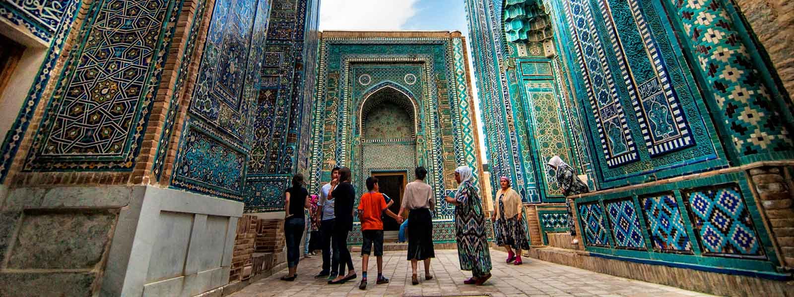 A group of people walking down an alley with blue tiled walls.