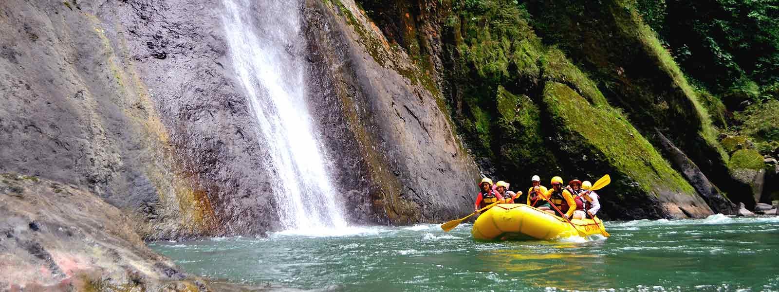 A group of people on an adventure travel south america tour rafting down a river near a waterfall.