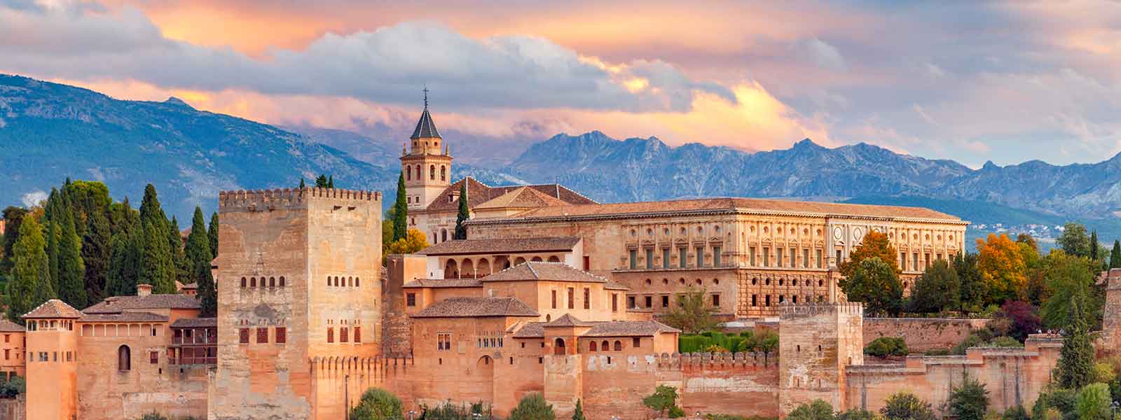 The city of granada at sunset with mountains in the background.