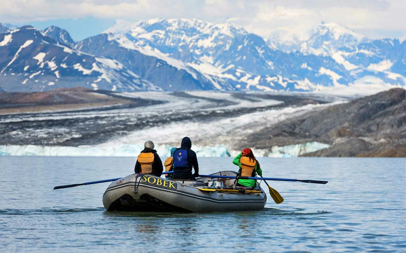 Three people on a boat with a glacier in the background.