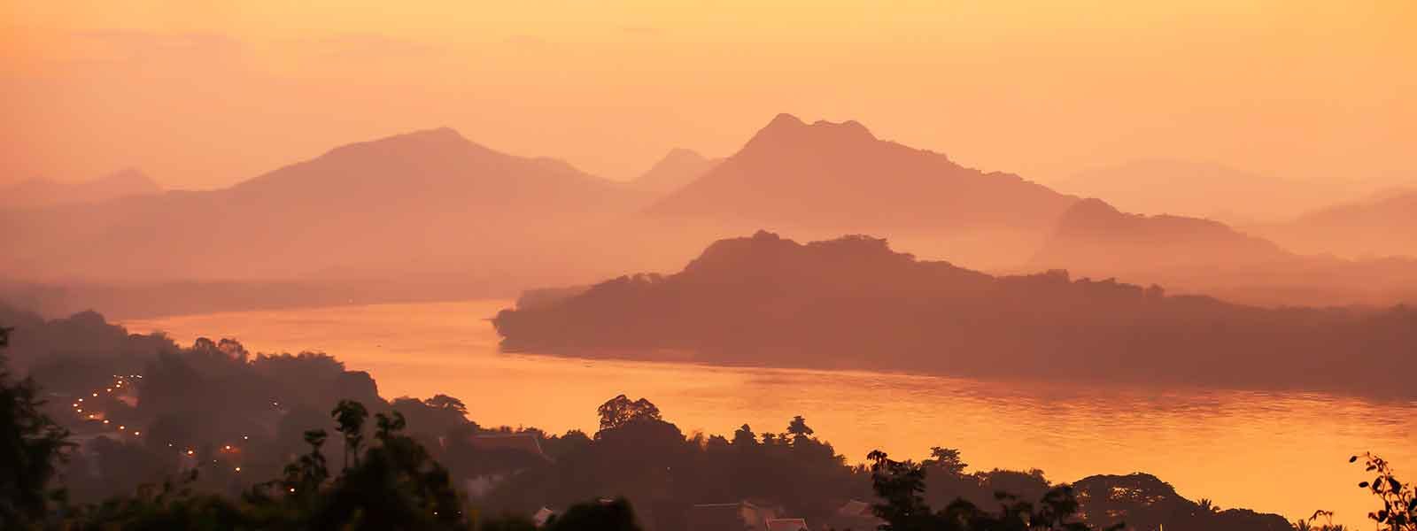 A sunrise over a river and mountains.