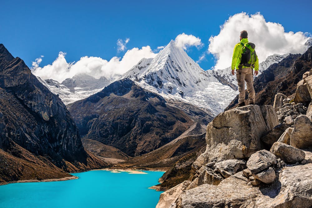 A man standing on top of a mountain overlooking a lake.
