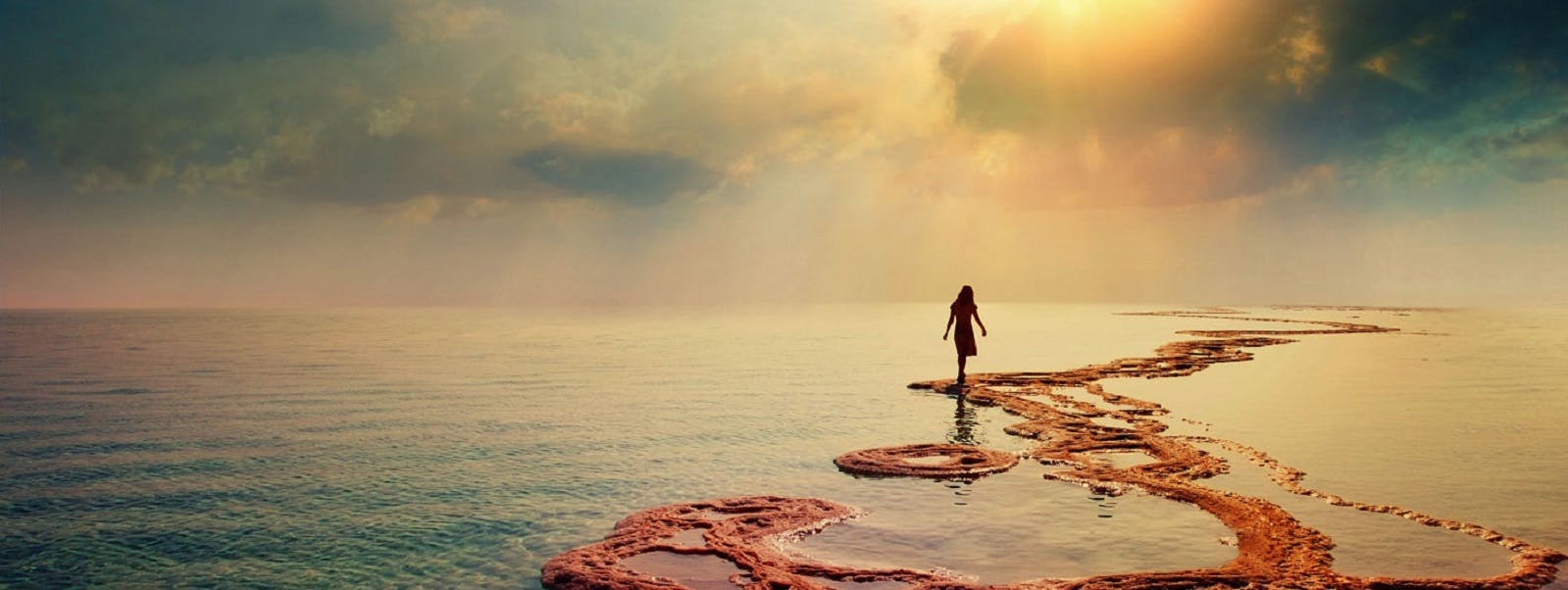 A person standing on a rocky shore in the ocean.