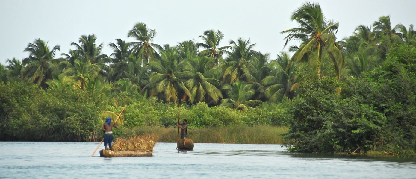 Two people travel through the waterways of Togo by traditional boat