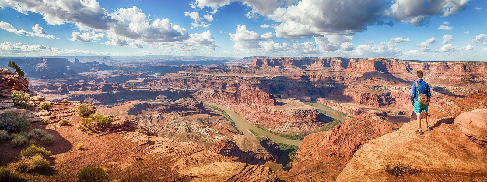 A man is standing on a cliff, marveling at the grandeur of the Grand Canyon during one of the best private adventure tours.
